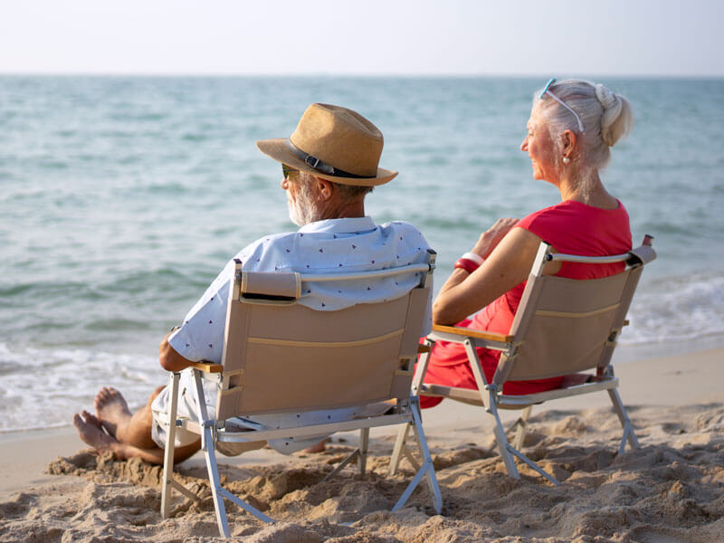 Senior couple sitting and talking at the beach